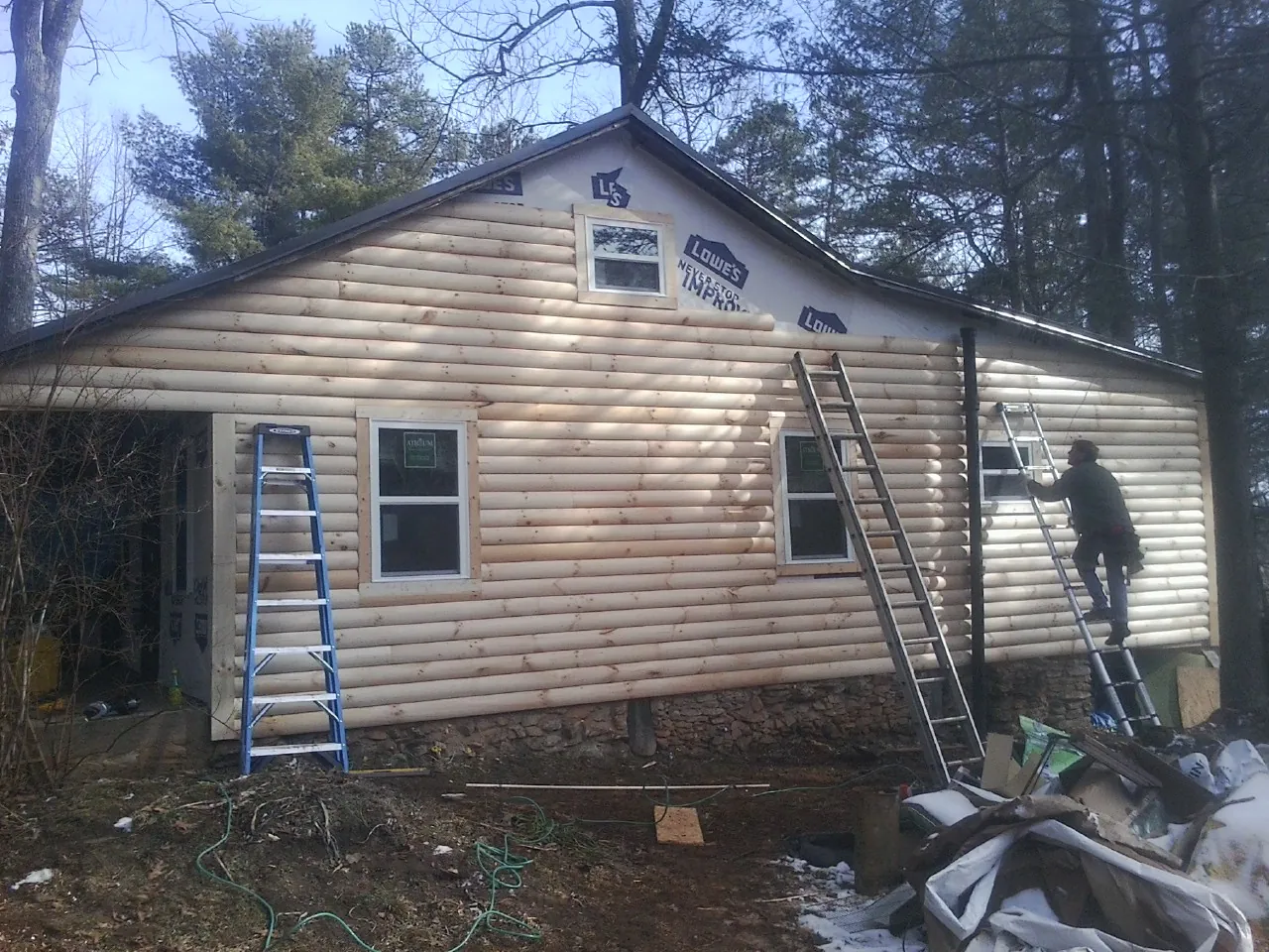 Ladders set against fresh log siding during an exterior remodel in Sparta