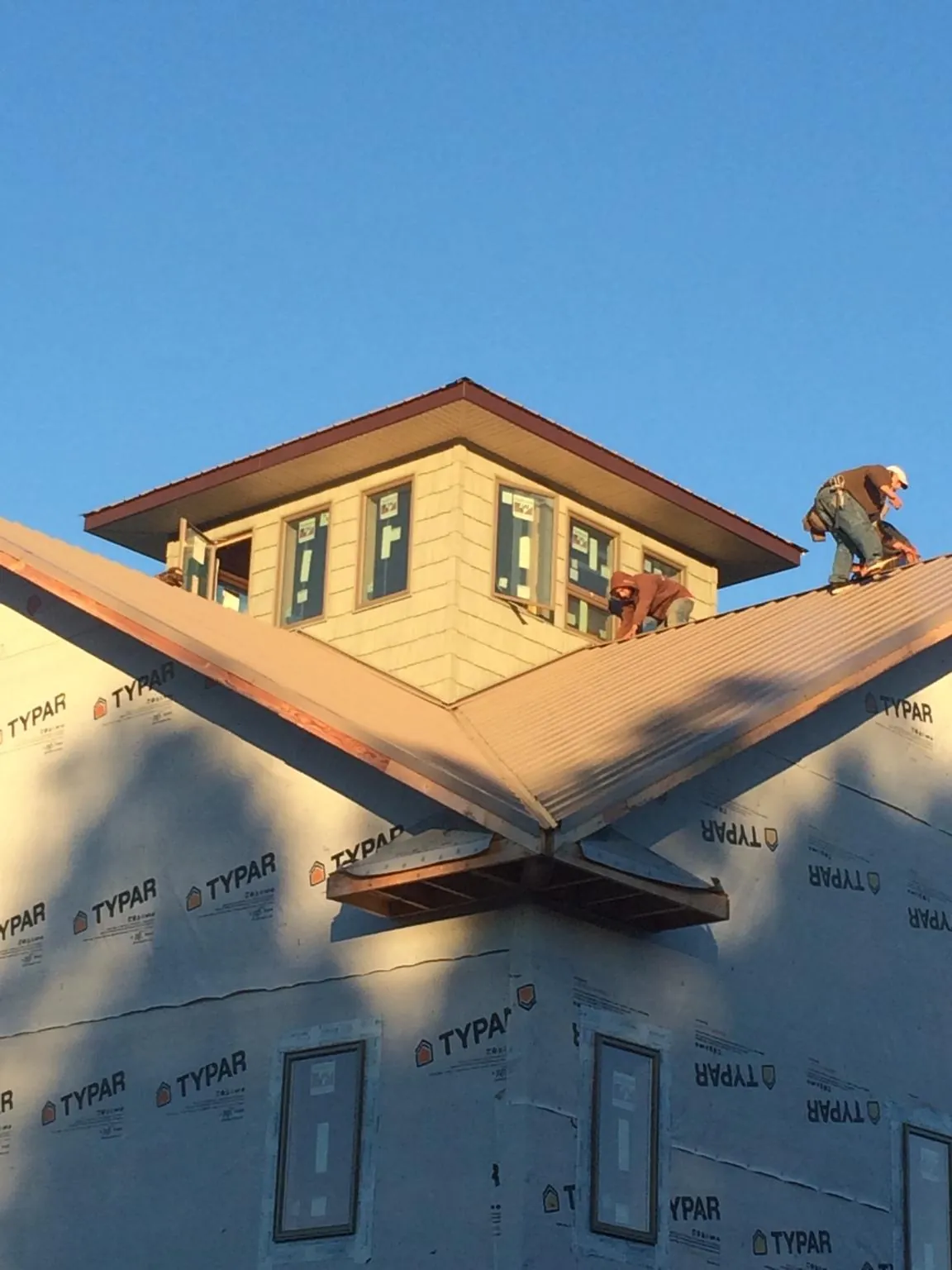 Roofers working around a rooftop cupola on a new metal roof at sunset — Roof Waterproofing in Sparta by Roofing Brothers